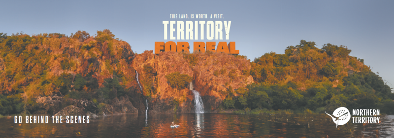 Image of Wangi Falls. With text overlay saying This Land. Is Worth. A Visit. The Territory For Real. Go Behind the Scenes. With the NT logo. 